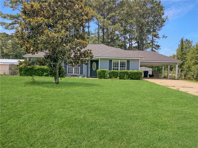 A classic ranch home nestled among mature trees with a well-maintained lawn.
