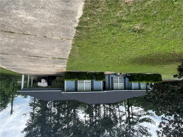 This inviting residence features a well-maintained exterior, a spacious lawn, and a convenient covered parking area.