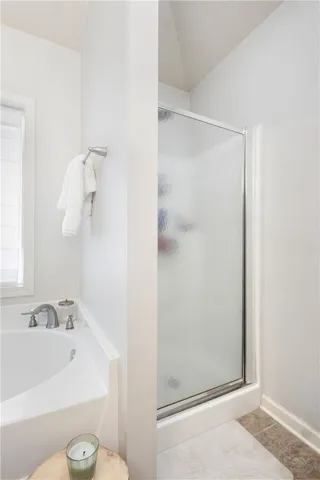 This primary bathroom features a tub and a glass-enclosed shower.