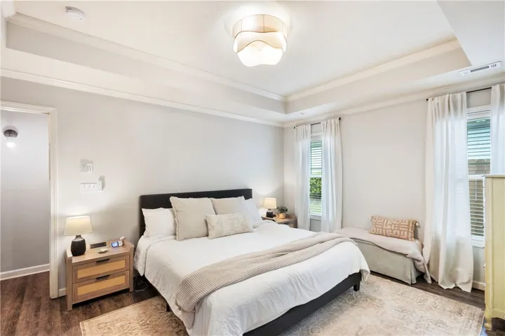 This tranquil bedroom offers comfort and style with elegant tray ceilings and abundant natural light.