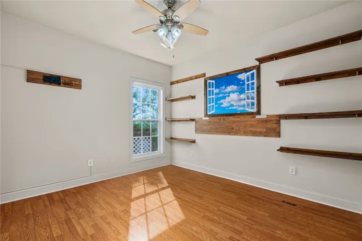 Natural light illuminates rich hardwood floors in this adaptable room, ideal for a study or creative space.