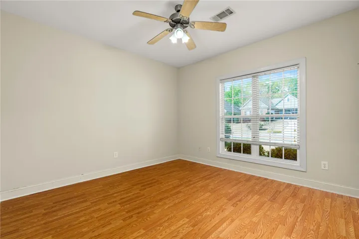 A well-lit room with warm hardwood floors and a window overlooking a quiet neighborhood street.