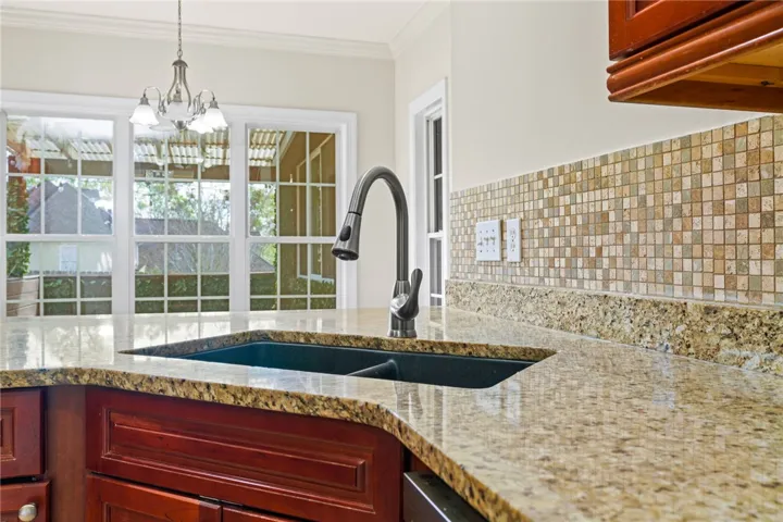 Premium granite counters and a stylish mosaic backsplash elevate this well-appointed kitchen.