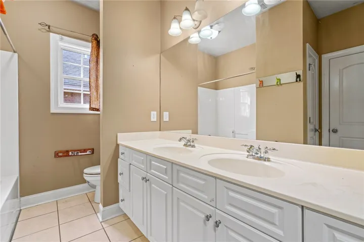 Double vanity offers ample space in this well-lit bathroom.