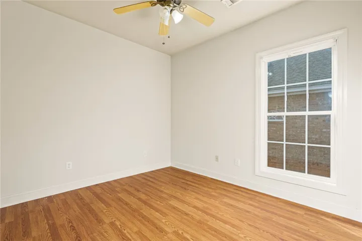A quiet room featuring rich wood flooring and a refreshing ceiling fan for ultimate comfort.