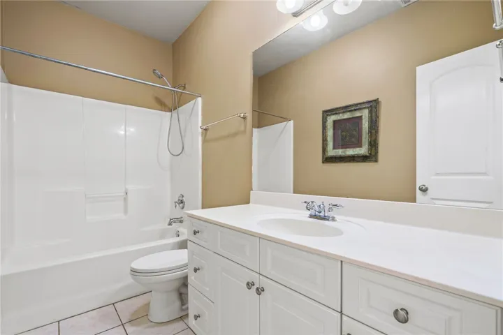 Functional bathroom featuring a tub-shower combination, single vanity, and convenient storage options.