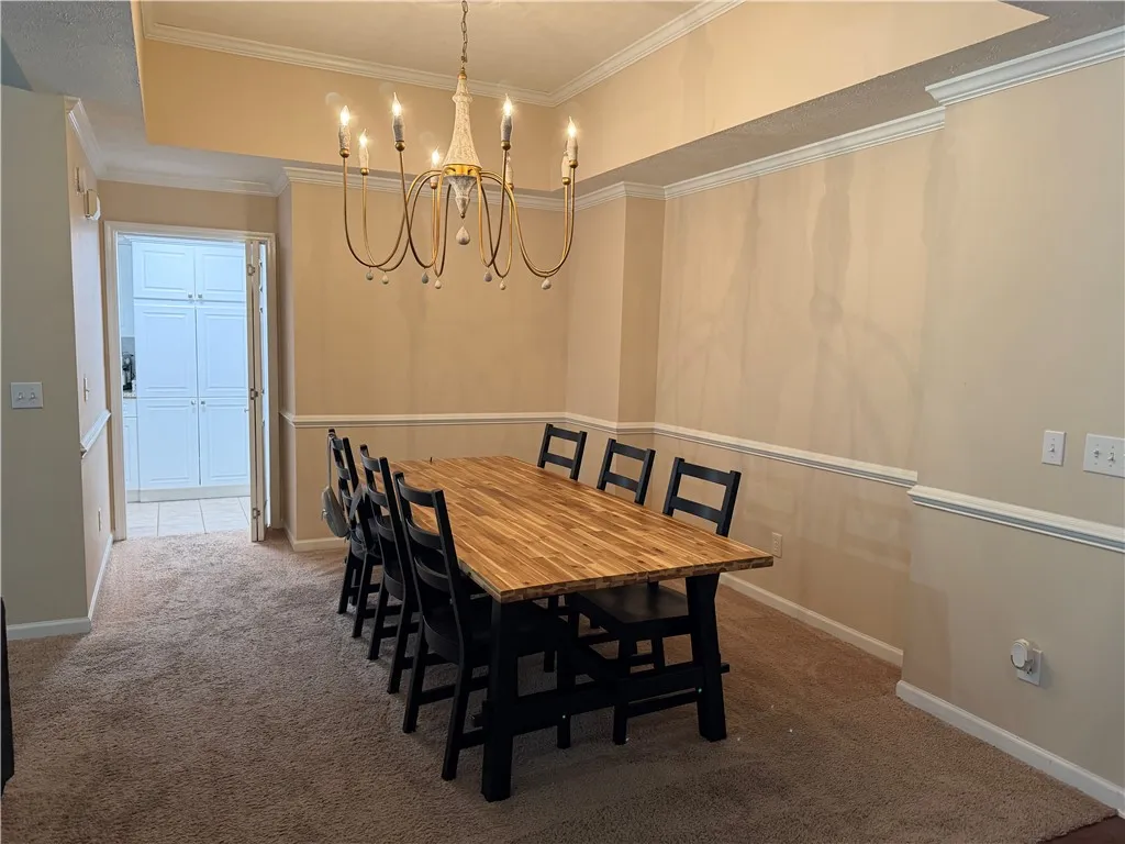This formal dining space features carpet flooring and an elegant chandelier, perfect for memorable gatherings.