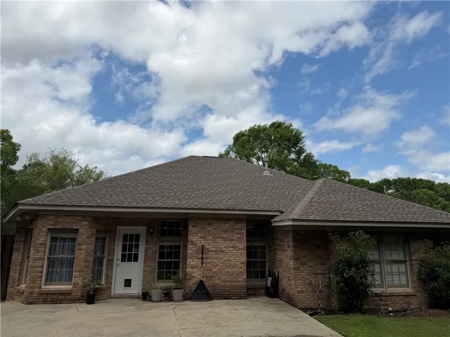 This classic brick residence features a durable shingle roof and a welcoming front entrance.