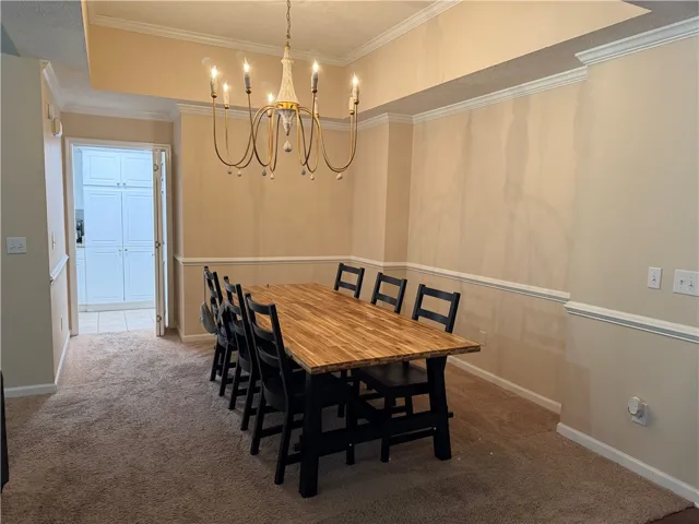 This formal dining space features carpet flooring and an elegant chandelier, perfect for memorable gatherings.