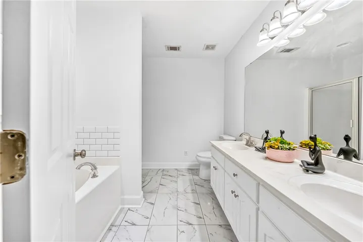 This bright bathroom features dual vanities and a combination bathtub and shower.