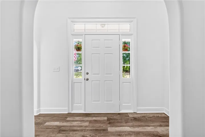 Enter into a bright foyer featuring beautiful hardwood flooring and a classic paneled door.