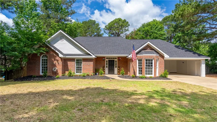 This charming home features classic brick and white siding, surrounded by lush trees and a well-maintained lawn.