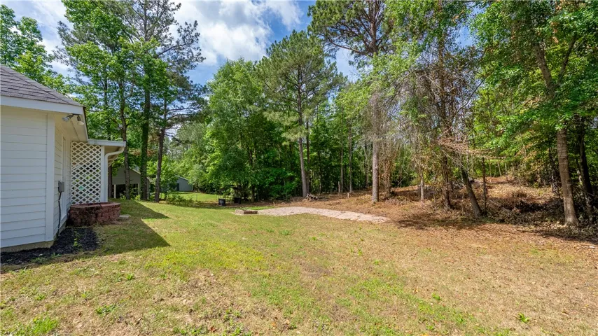 This spacious backyard offers ample outdoor living potential, surrounded by natural beauty and mature trees.