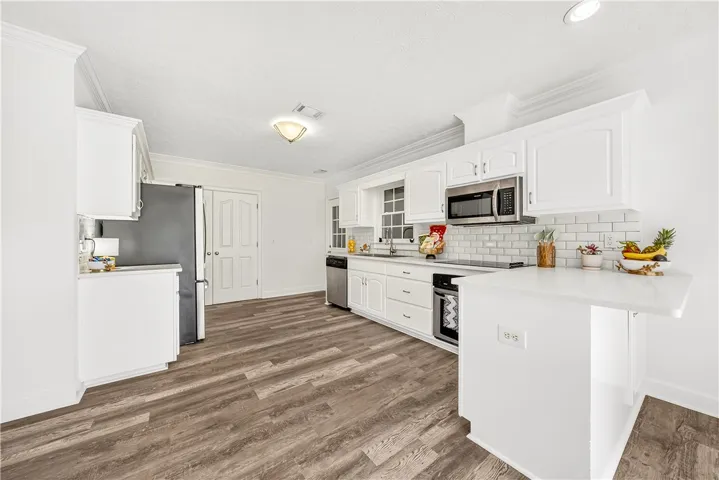 This bright kitchen features classic white cabinetry and durable wood-look flooring.