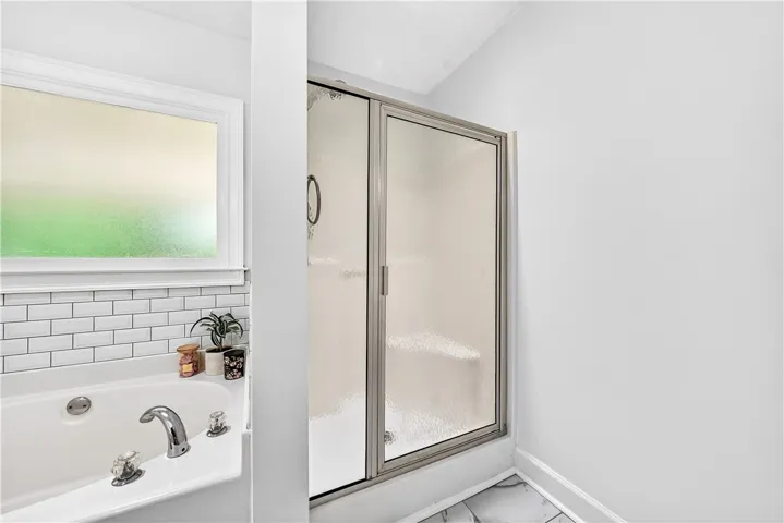 This primary bathroom offers a bright window above the tub and a spacious standing shower.