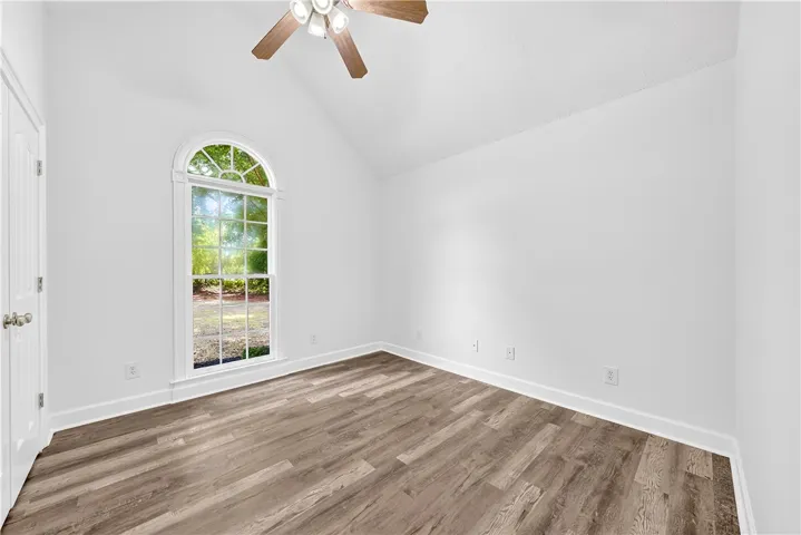 This airy room features a vaulted ceiling and a large arched window, offering abundant natural light.