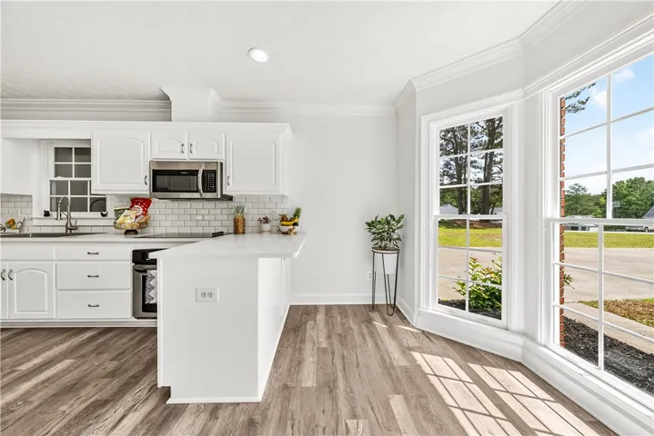 This bright kitchen features white cabinetry and expansive windows, creating an inviting culinary space.
