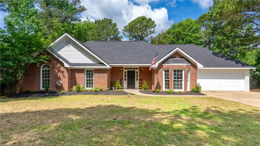 This charming brick home features an attached garage and a well-maintained front yard.