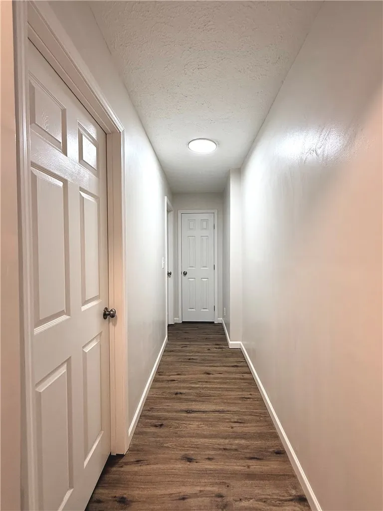 This interior hallway features beautiful wood flooring, leading to several well-maintained doors.