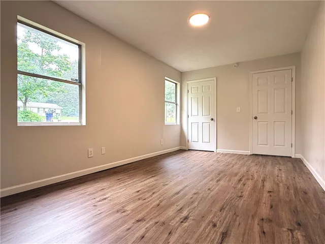 Bright and airy room with durable wood-look flooring and multiple access points.