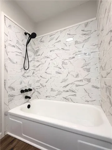 This bathroom features a sleek tub and shower combination with stylish tiled walls.