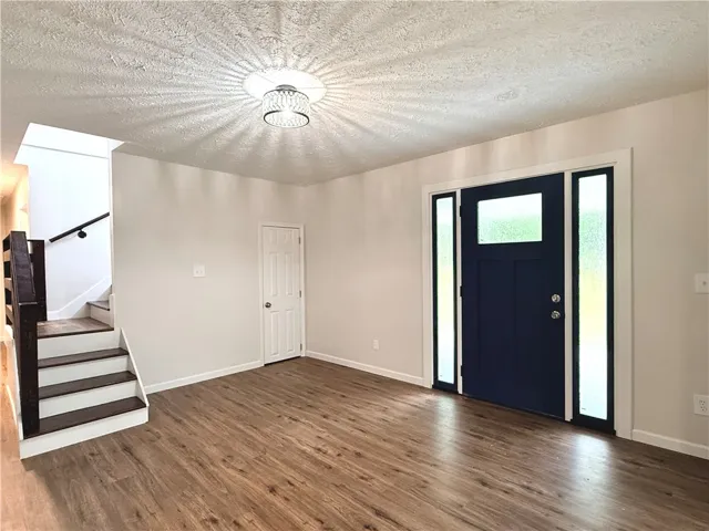 Enter into this inviting space, featuring rich wood-look flooring and a prominent entry door.