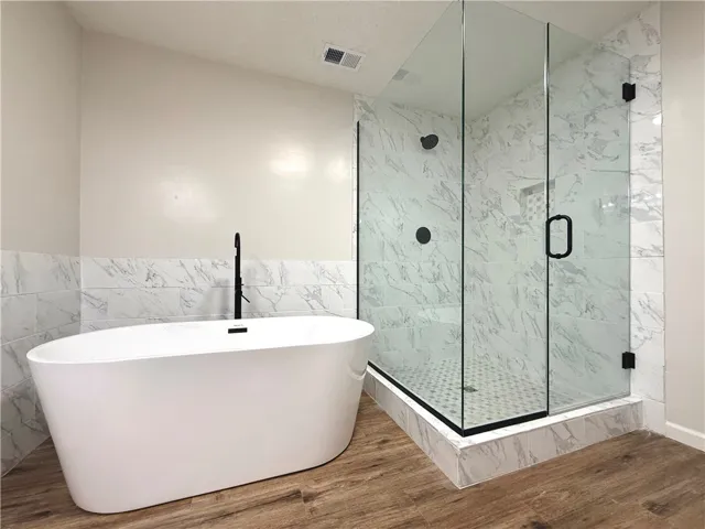 This spacious bathroom offers a luxurious soaking tub and a sleek, modern glass-enclosed shower.