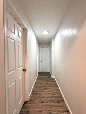 This interior hallway features beautiful wood flooring, leading to several well-maintained doors.