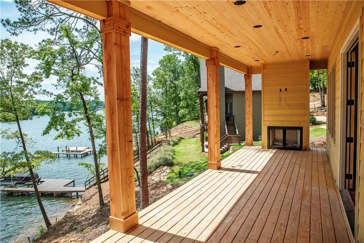 Enjoy tranquil lake views from this expansive wooden deck, featuring a built-in fireplace.