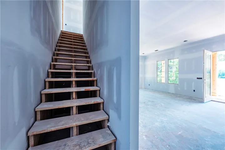 This interior captures a spacious area featuring a prominent staircase, multiple windows, and French doors.