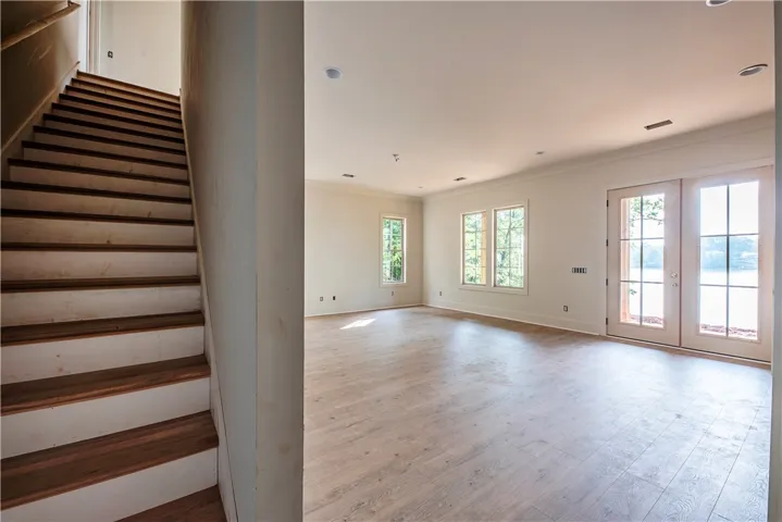 A spacious room with bright windows and French doors opens to the outdoors, complementing the warm flooring and ceiling details.