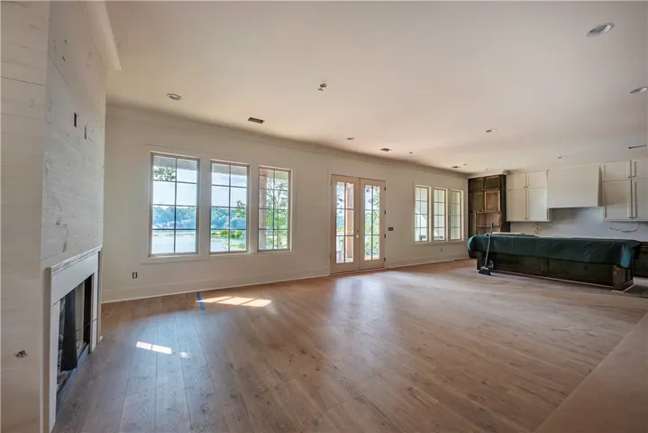Luminous living space with hardwood floors and a striking fireplace, opening to a scenic waterfront.