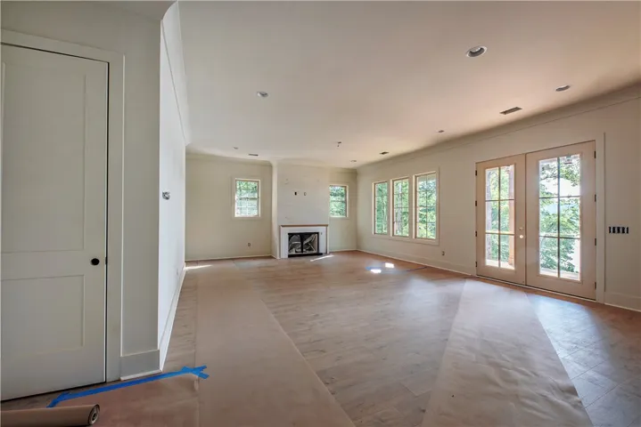A spacious, naturally illuminated living area featuring rich wood flooring and a classic fireplace.
