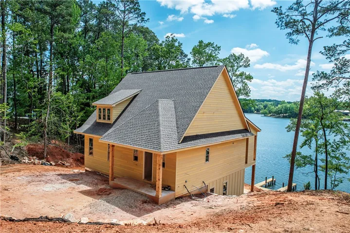 This newly constructed home features a classic gable roof and wood siding, offering tranquil lake views.