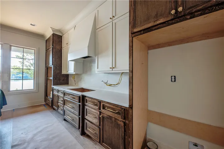 Newly constructed kitchen space awaits your personal touch, featuring ample cabinetry and a serene window view.