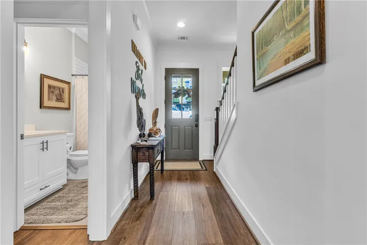 This inviting entry features hardwood flooring and a glimpse into a well-appointed bathroom.