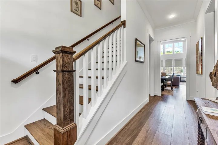 This inviting hallway features rich wood flooring and a beautifully crafted staircase, leading to an open living area.