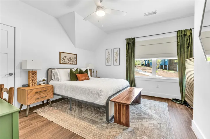 This bright bedroom features a vaulted ceiling and ample natural light through a large window.