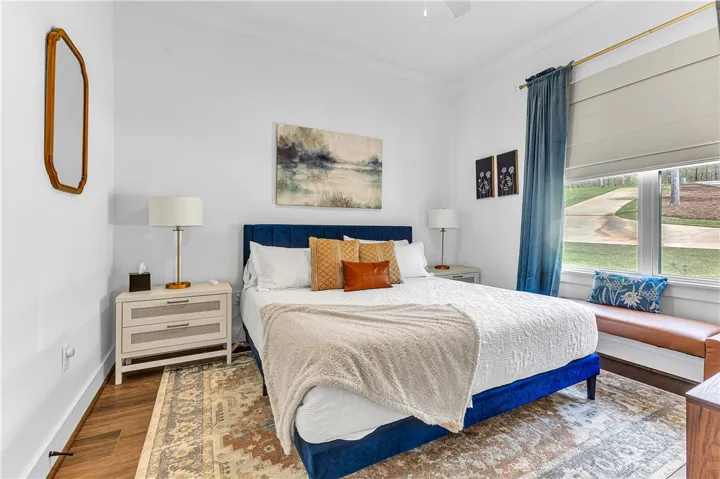 This cozy bedroom features warm wooden flooring and abundant natural light.