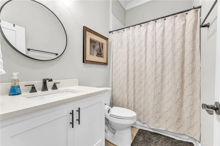 This clean and bright bathroom features a vanity with sleek fixtures and a shower with a privacy curtain.