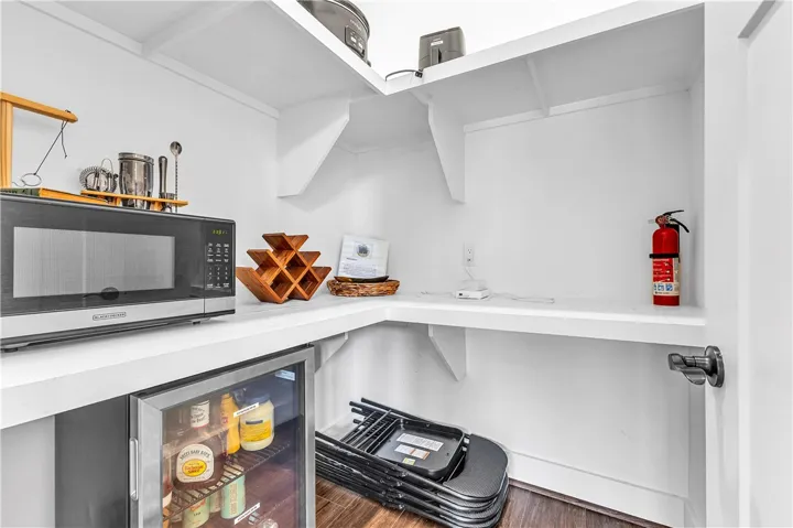 This organized pantry features practical shelving and convenient appliances for everyday needs.