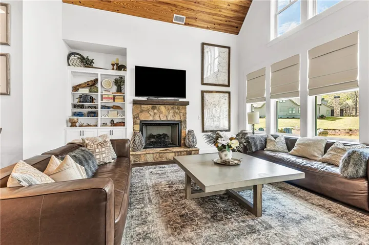 This bright living space features high ceilings and a cozy fireplace, perfect for relaxation and gatherings.