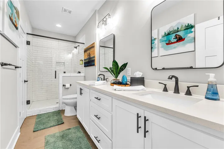 This bright bathroom features a spacious dual vanity, a walk-in shower, and ample storage.
