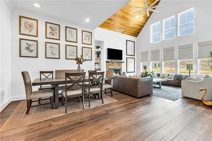 Bright and open living area with vaulted wood ceilings, large windows, and sleek flooring.