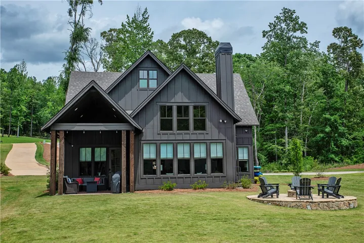This modern farmhouse features a charming covered patio and an inviting outdoor fire pit.