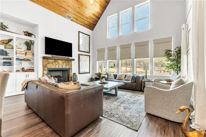 This living room features vaulted wood ceilings, a stone fireplace, and ample natural light.
