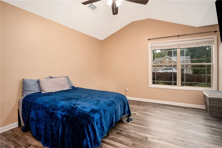 This spacious bedroom features a vaulted ceiling, durable laminate flooring, and ample natural light.