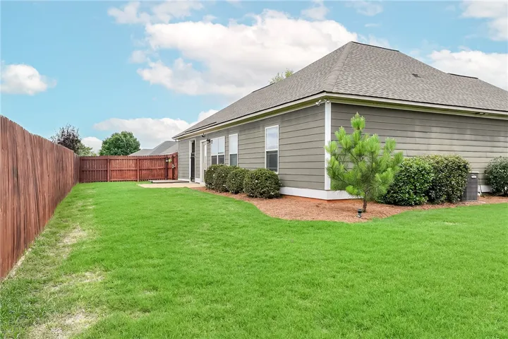 This residence features a private yard with a wooden fence and a lush green lawn.