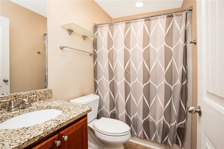 This clean bathroom features a spacious shower and elegant granite countertops.