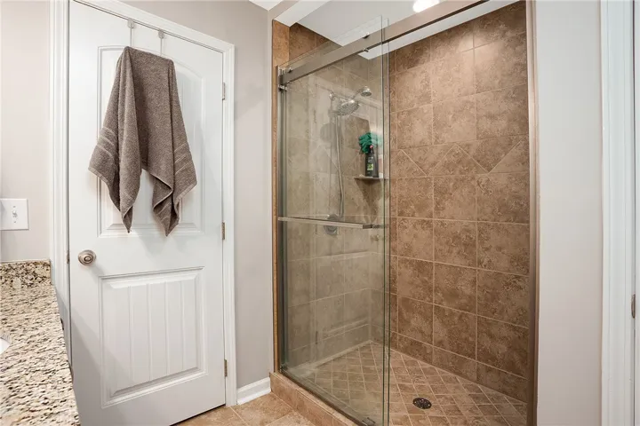 This bathroom features a sleek glass-enclosed shower with tiled walls and a functional showerhead.